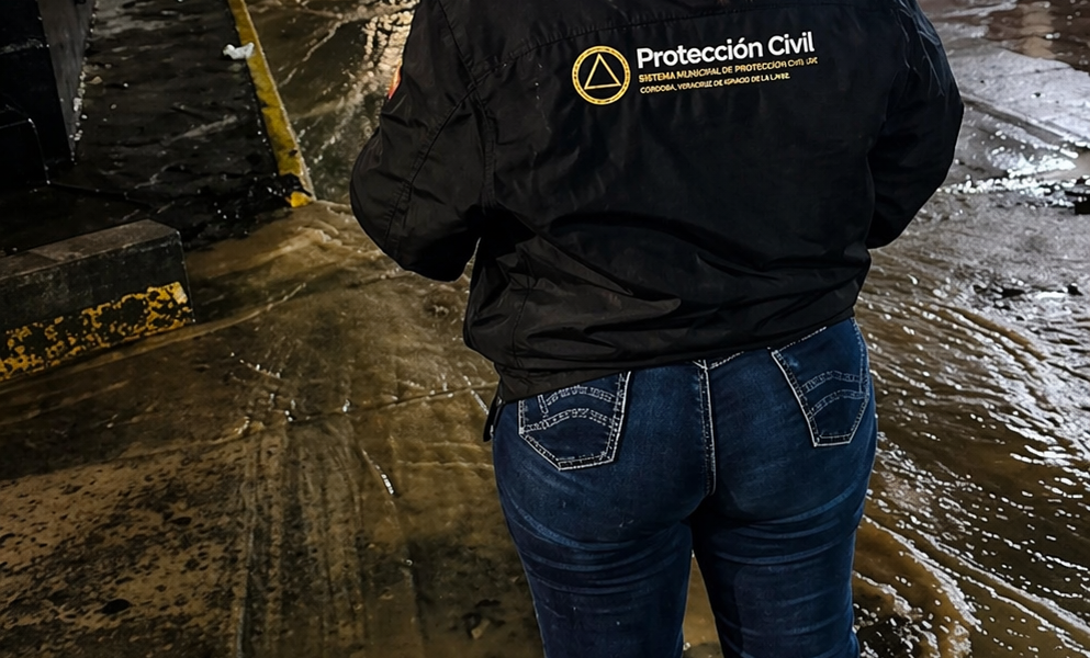 Elemento de Protección Civil supervisando calle inundada en Atlixco durante la noche tras lluvias
