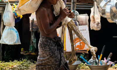 Hombre camina cargando restos humanos envueltos en tela en un mercado de India.