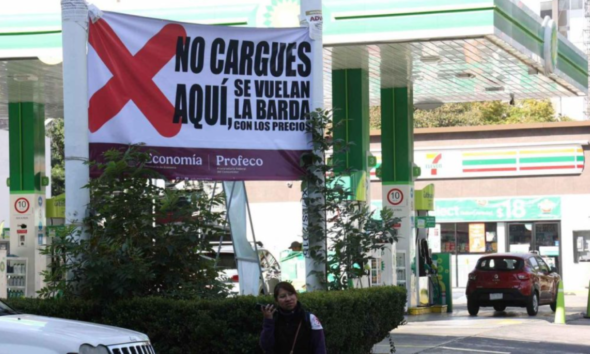 Lona de Profeco en gasolinera alertando sobre precios altos de combustible
