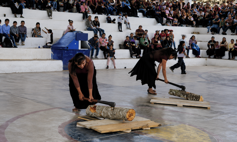 Mujeres participando en concurso de corte de troncos durante celebración comunitaria en Chiapas