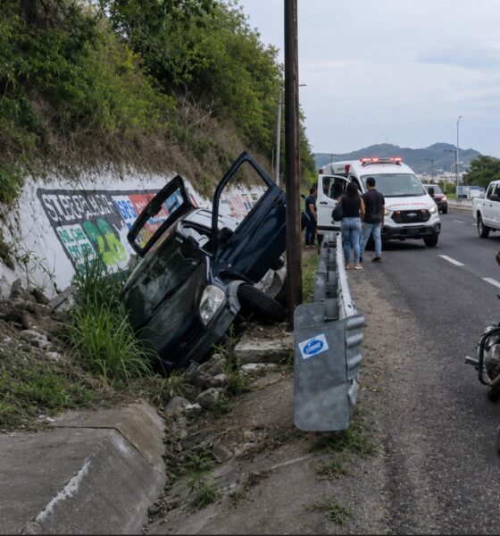 Automóvil accidentado dentro de una zanja en la carretera federal Puebla–Atlixco a la altura del kilómetro 28, mientras paramédicos atienden a una familia lesionada.