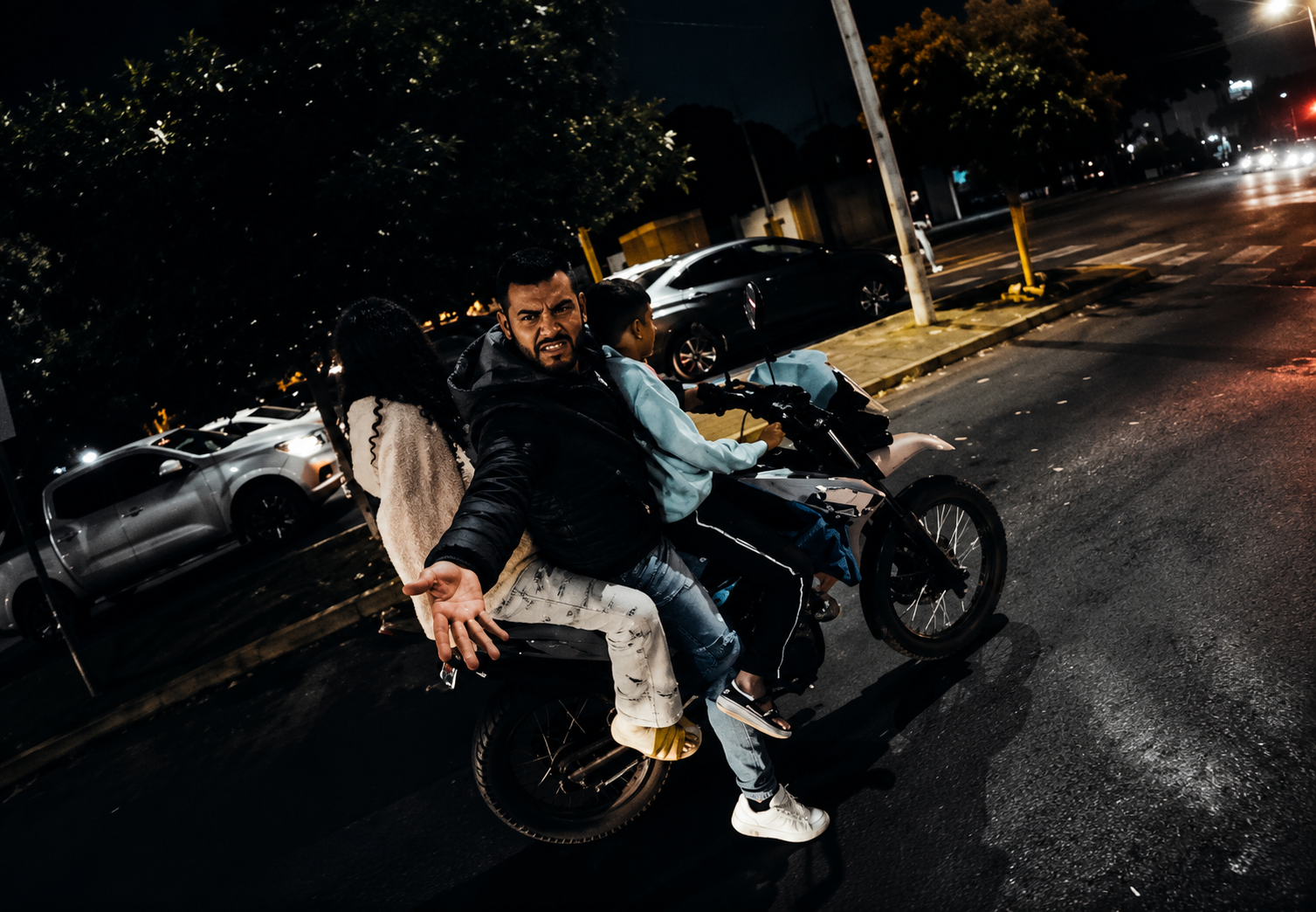 Motocicleta transportando a varios pasajeros sin equipo de protección durante la noche, ejemplo de riesgos de seguridad vial y conducción imprudente en México.