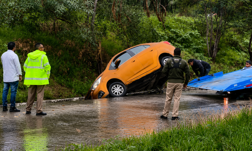 Automóvil color naranja dentro de una cuneta tras derrapar sobre pavimento mojado en la carretera federal Puebla-Atlixco durante temporada de lluvias.