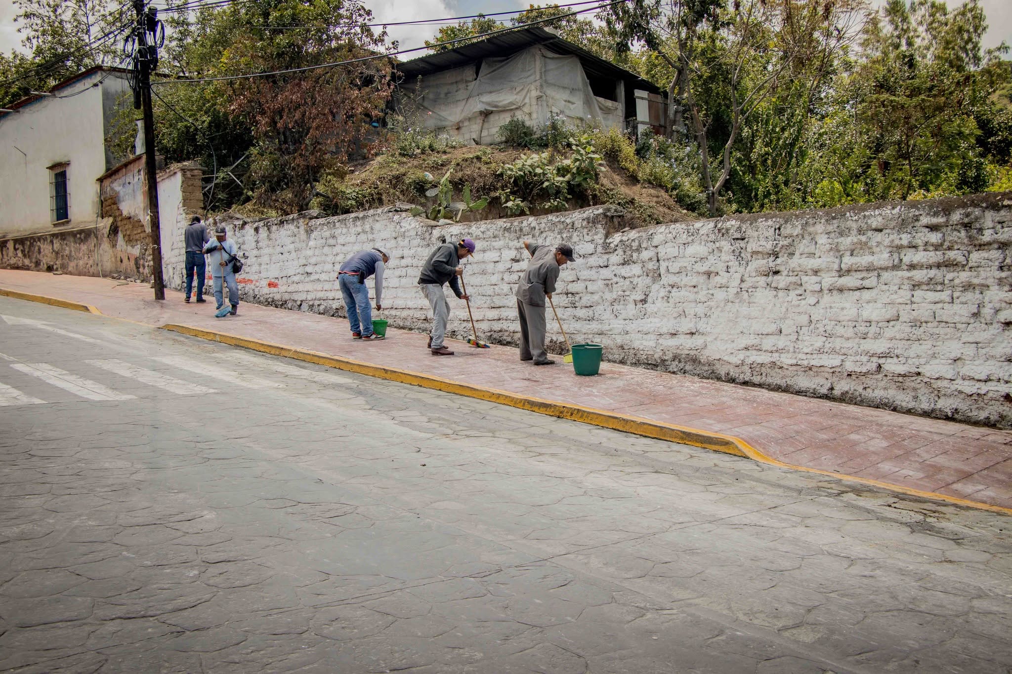 Personal de Servicios Públicos Municipales realizando labores de limpieza en una calle principal de Tochimilco como parte del programa de mejoramiento de la imagen urbana.