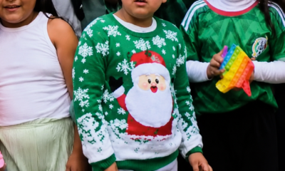 Niño mexicano con suéter navideño verde entre aficionados de la Selección Mexicana durante actividades relacionadas con el Mundial 2026.