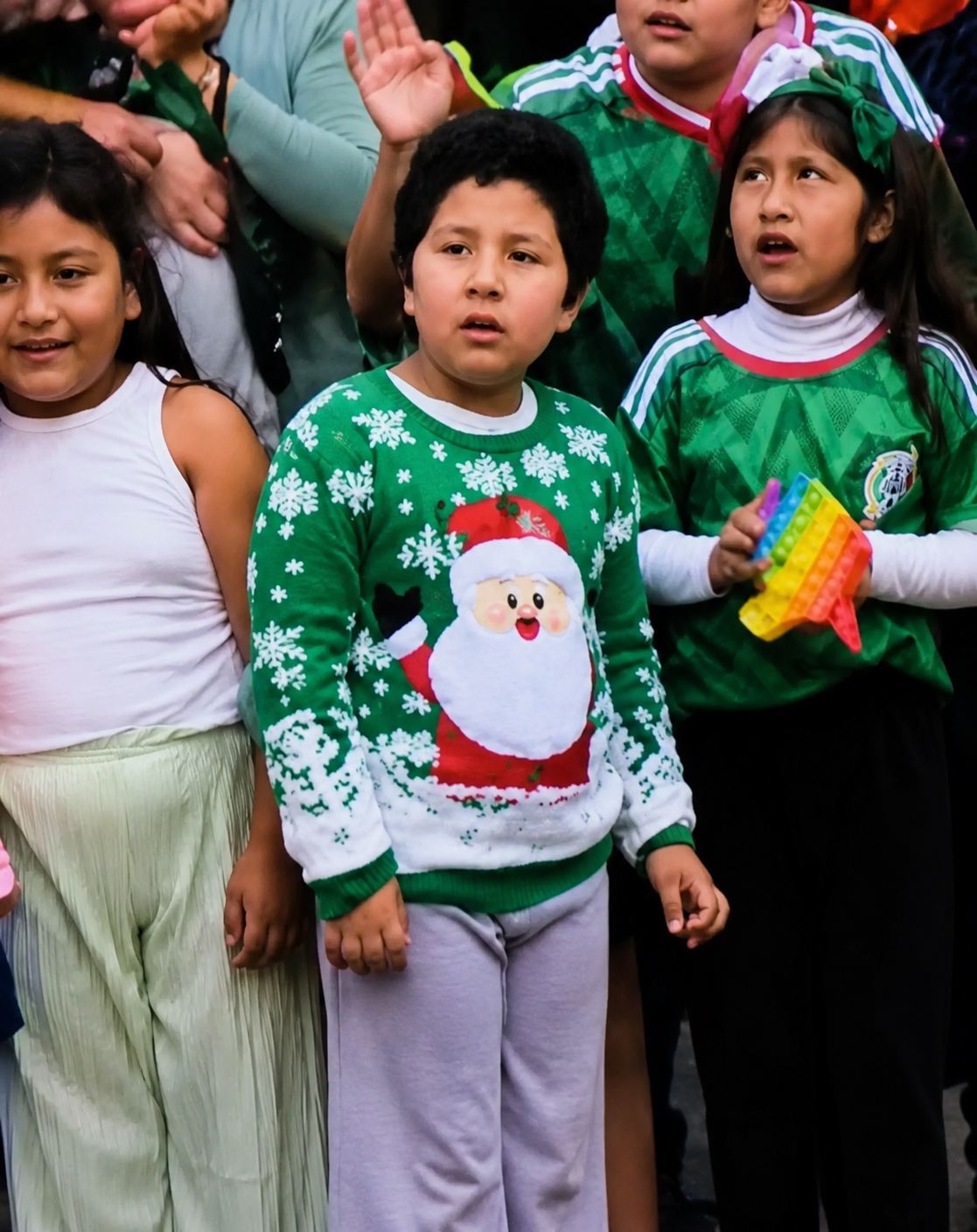 Niño mexicano con suéter navideño verde entre aficionados de la Selección Mexicana durante actividades relacionadas con el Mundial 2026.