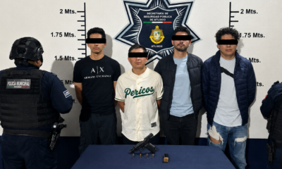 # Texto ALT Cuatro hombres detenidos por elementos de la Secretaría de Seguridad Pública de Atlixco tras una persecución en la colonia Álvaro Obregón. En la mesa de indicios se observa un arma corta, cartuchos útiles y un cargador asegurados durante el operativo. --- # Título de la imagen Detienen a cuatro hombres en Atlixco; aseguran arma de fuego tras persecución --- # Leyenda Elementos de la Secretaría de Seguridad Pública de Atlixco presentaron a cuatro hombres detenidos luego de una persecución derivada de un reporte ciudadano. Durante el operativo fue asegurada un arma corta abastecida, cartuchos útiles y un cargador, los cuales quedaron a disposición de la autoridad competente para las investigaciones correspondientes. --- # Descripción Fotografía oficial de la **Secretaría de Seguridad Pública de Atlixco** en la que aparecen **cuatro hombres detenidos** tras una persecución registrada en la colonia **Álvaro Obregón**, en el municipio de Atlixco, Puebla. La intervención policial inició luego de que una ciudadana reportó un **vehículo Mazda color rojo** que circulaba con las luces apagadas y cuyos ocupantes presuntamente realizaron detonaciones de arma de fuego al aire. Tras un operativo de búsqueda, elementos municipales interceptaron la unidad sobre la **calle 9 Poniente número 113**. Durante la inspección del vehículo, los oficiales localizaron un **cartucho percutido** y posteriormente aseguraron un **arma corta abastecida con cartuchos útiles**, la cual se encontraba debajo del asiento del conductor. En la imagen también se aprecia el armamento asegurado colocado sobre una mesa de indicios, acompañado por el cargador y la munición correspondiente. Los cuatro detenidos fueron puestos a disposición de la autoridad competente, que será la encargada de determinar su situación jurídica conforme al debido proceso. Es importante señalar que, de acuerdo con la legislación mexicana, toda persona detenida goza del derecho a la **presunción de inocencia** hasta que exista una resolución judicial firme. La imagen ilustra una acción de seguridad pública derivada de la atención a un reporte ciudadano y sirve como apoyo visual para informar sobre los resultados del operativo realizado por la Policía Municipal de Atlixco, así como para destacar la importancia de la denuncia oportuna en la prevención y combate de hechos delictivos.