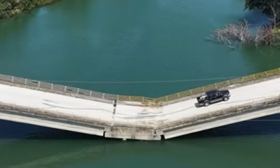 Puente con aparente colapso estructural por el que continúa circulando un vehículo.