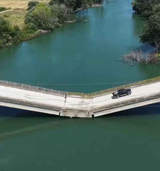 Puente con aparente colapso estructural por el que continúa circulando un vehículo.