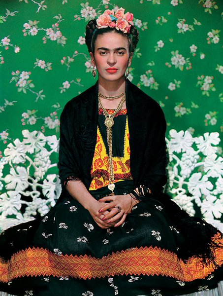 Retrato de Frida Kahlo con flores en la cabeza y vestimenta tradicional mexicana.