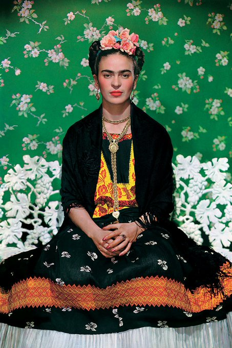 Retrato de Frida Kahlo con flores en la cabeza y vestimenta tradicional mexicana.