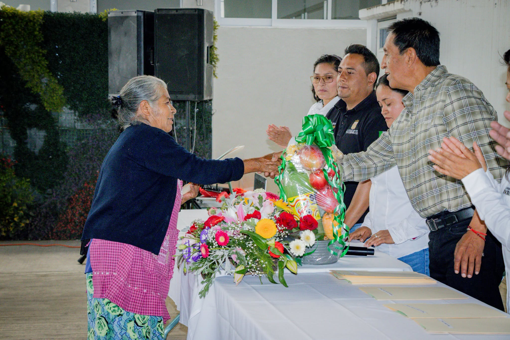 Adultos mayores de Tochimilco reciben sus visas del programa Reuniendo Familias durante una ceremonia encabezada por autoridades municipales.